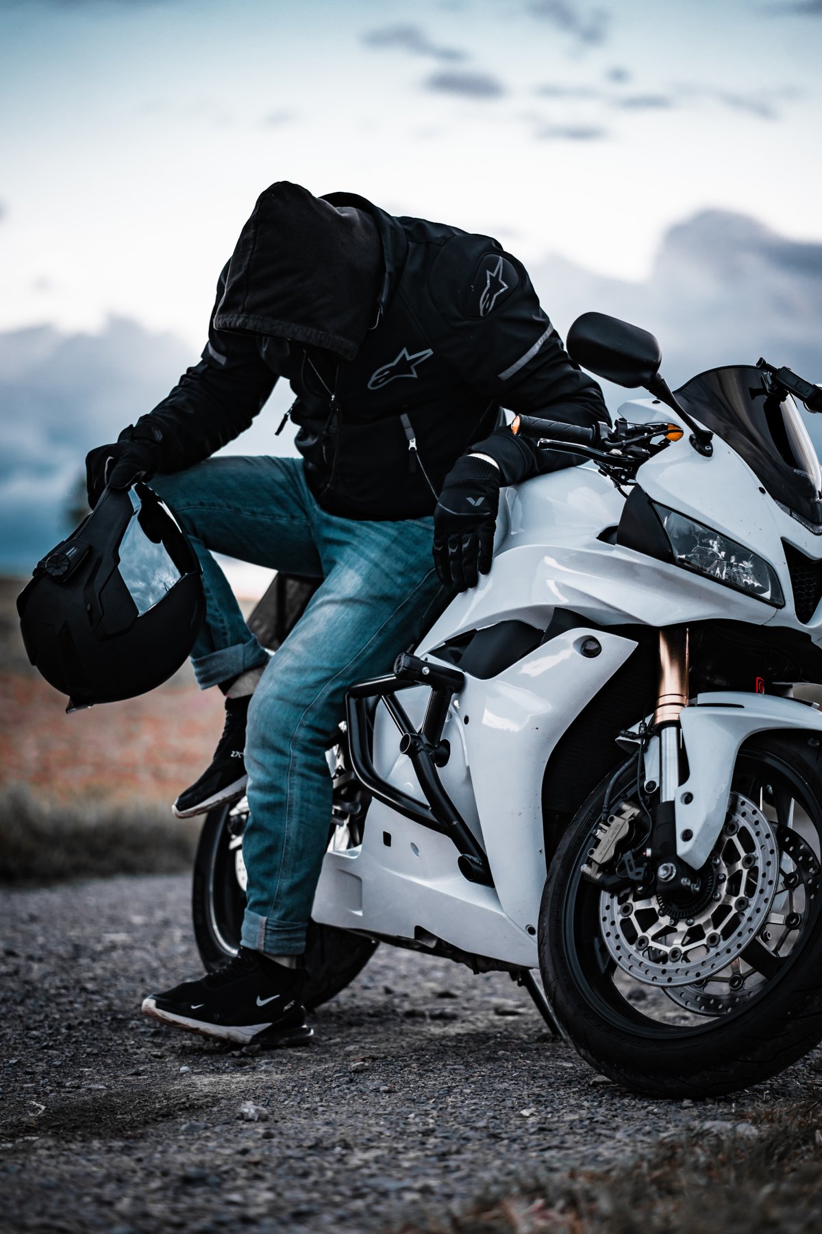 Tino in riding gear with his white sports bike, helmet in hand